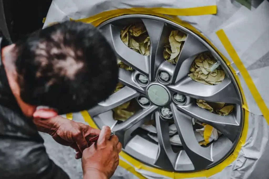 A man is learning how to repair an alloy wheel.