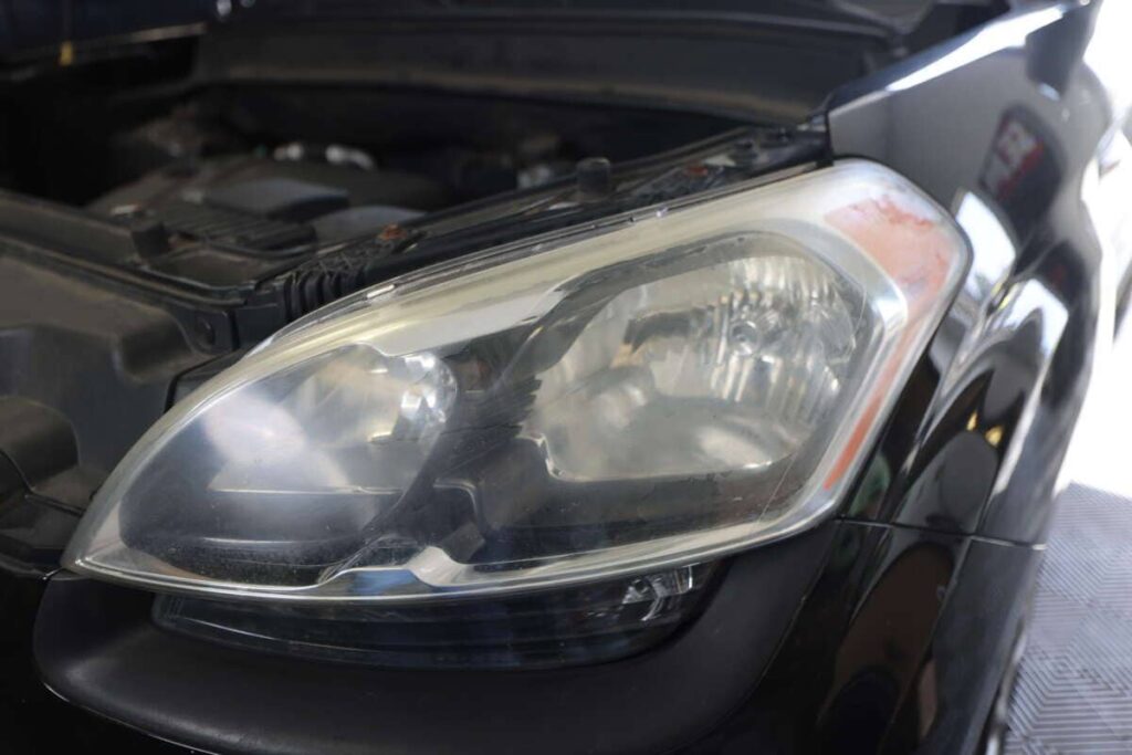 A car undergoing headlight renewal in a garage.