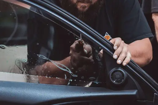A man with a beard installing window tint, highlighting the revenue potential for the Auto Recon industry.