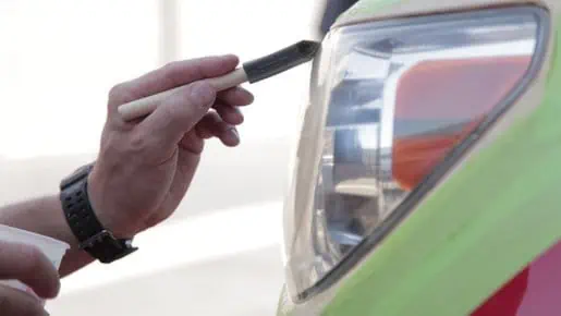 A man is utilizing a tool to enhance the revenue potential for the PDR industry by cleaning the headlight of a car.