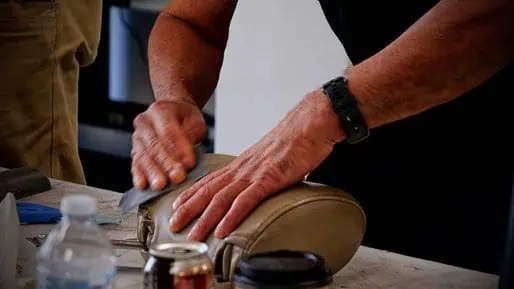 A man is sanding a leather head rest to enhance its revenue potential in the PDR industry.