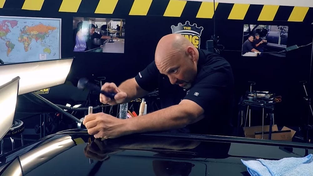 Using glue pulling techniques, a man is training in a shop to work on cars.