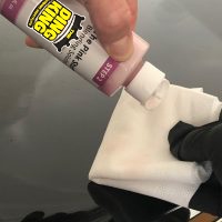 A hand holding a bottle of glue.