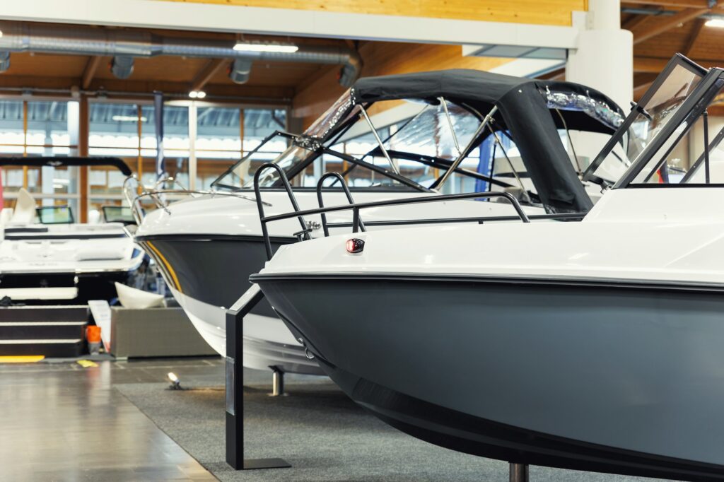 Several motorboats displayed inside a showroom with polished floors and bright lighting, perfectly showcasing their sleek designs and the benefits of Paint Protection Film Training.